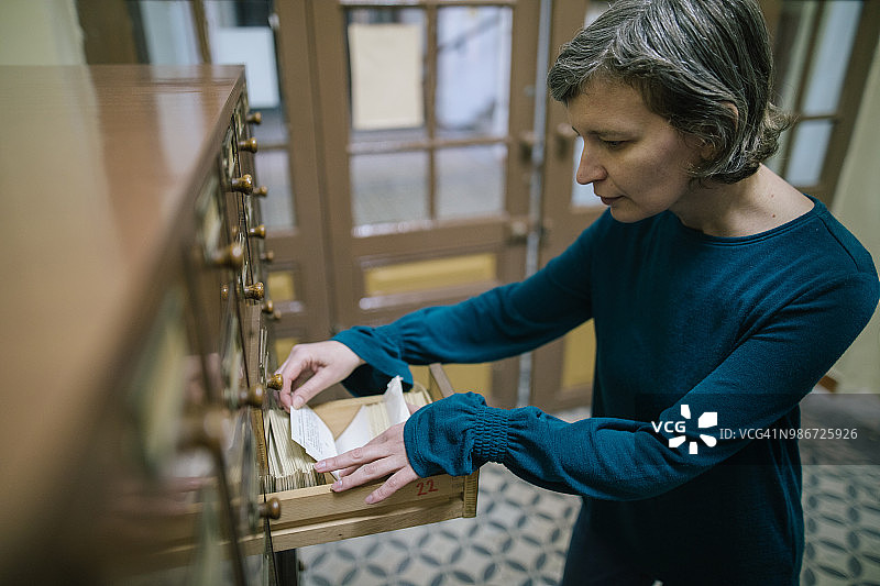 图书管理员在旧登记簿中查找索引卡图片素材