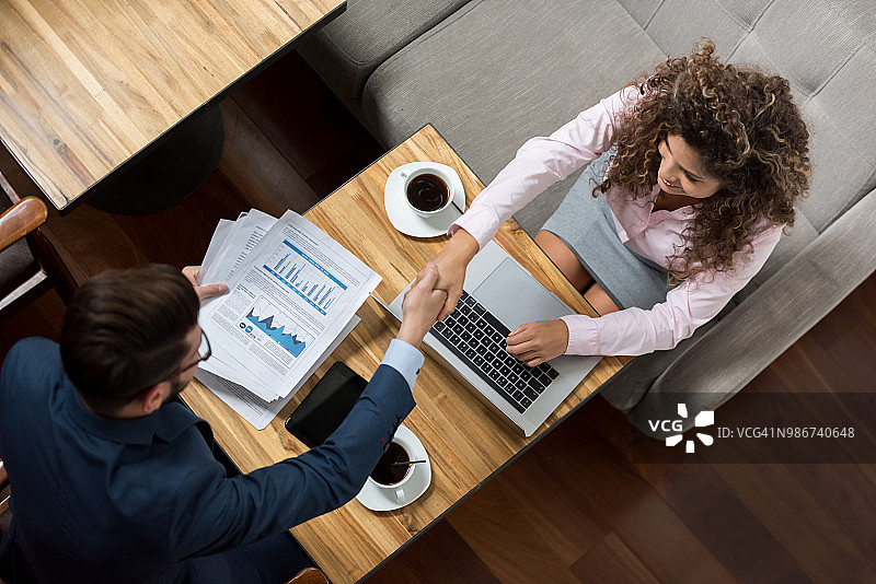 商务人士在餐厅通过握手达成交易图片素材