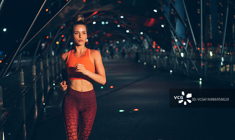 年轻女子在夜晚的桥上慢跑图片素材