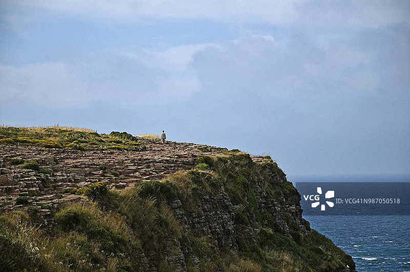 孤独的男人走在悬崖上欣赏迷人的景色，法国弗雷埃尔海角图片素材