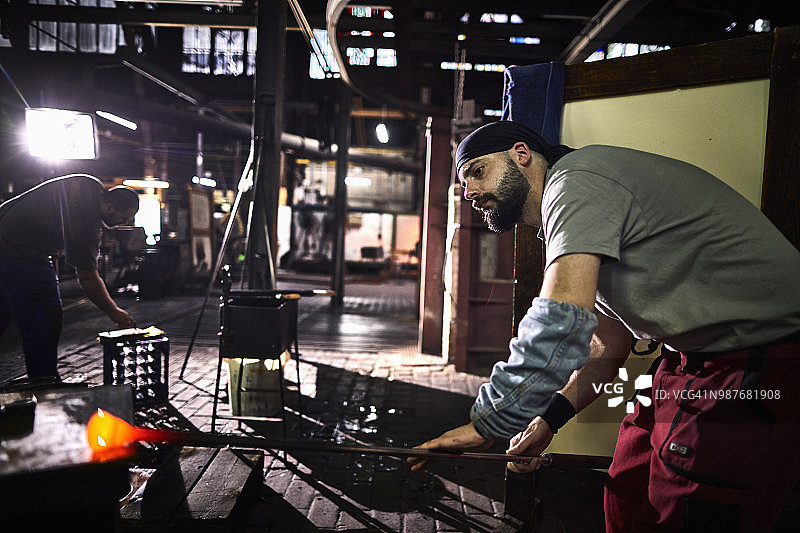 玻璃工厂中吹制发光玻璃的工人图片素材