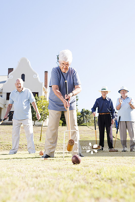 老年妇女满怀期待地看着她用木槌击球穿过球门图片素材