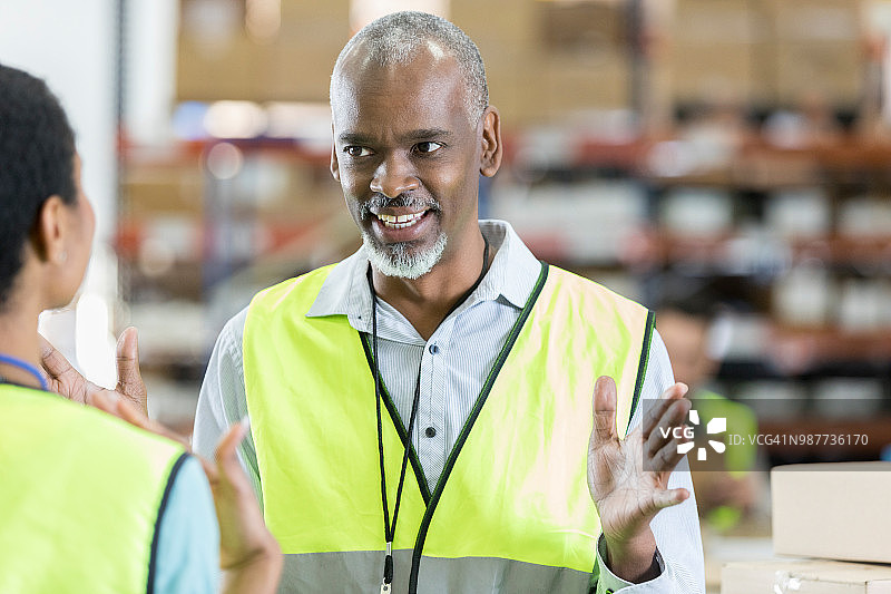 年长的配送仓库经理与女员工交谈图片素材
