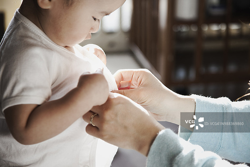 母亲帮她的男婴换衣服图片素材