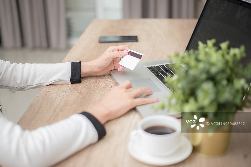 手持信用卡使用笔记本电脑，在线购物概念图片素材