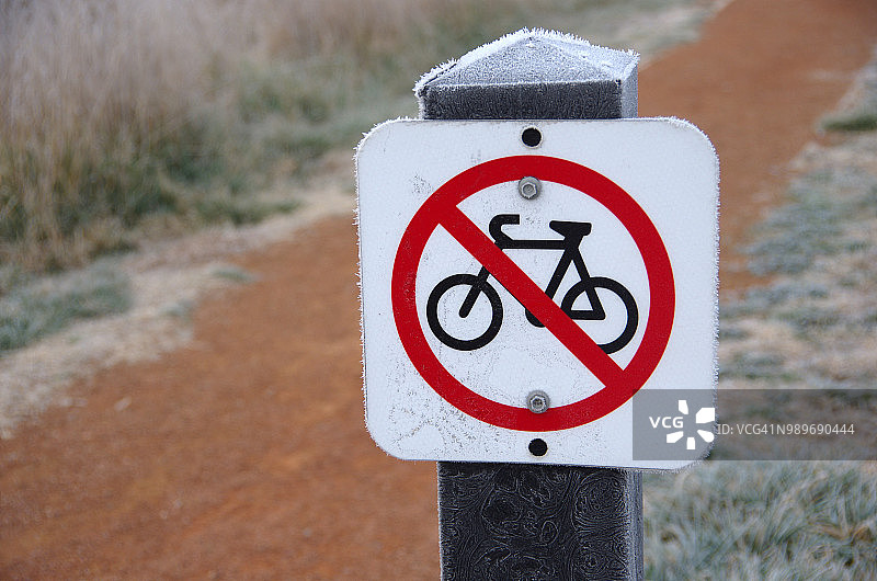 澳大利亚首都特区杰拉布姆伯拉湿地，泥泞小路旁的禁止自行车标志图片素材