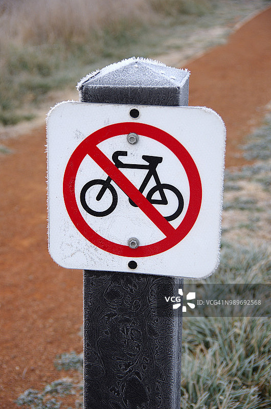 澳大利亚首都特区杰拉布姆伯拉湿地，泥泞小路旁的禁止自行车标志图片素材