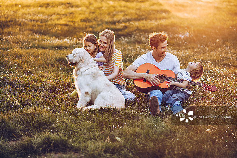 在春日公园里和他们的狗一起玩耍的快乐家庭图片素材