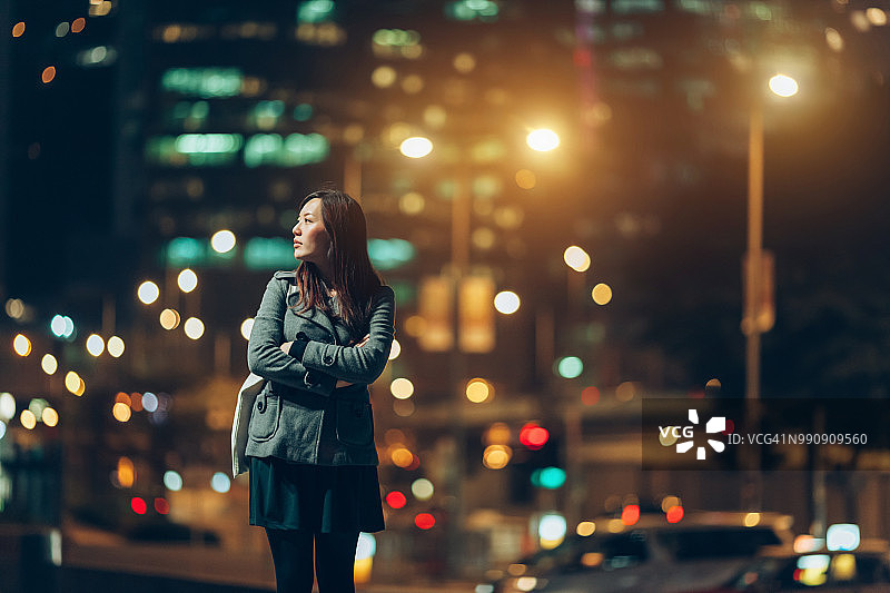 在繁忙的城市街道上等车的年轻女子图片素材