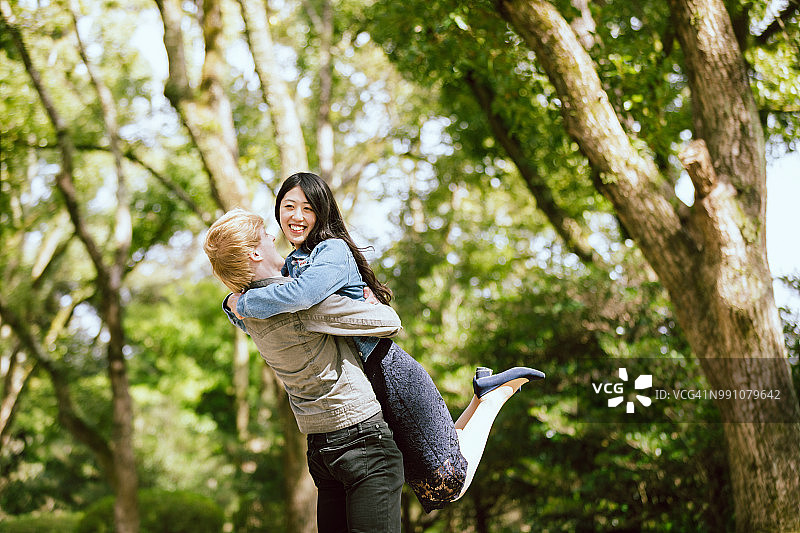 在翠绿公园里，白人男子与亚洲女性爱人图片素材