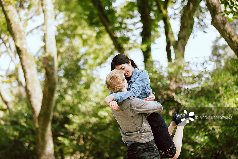 在翠绿公园里，白人男子与亚洲女性爱人图片素材