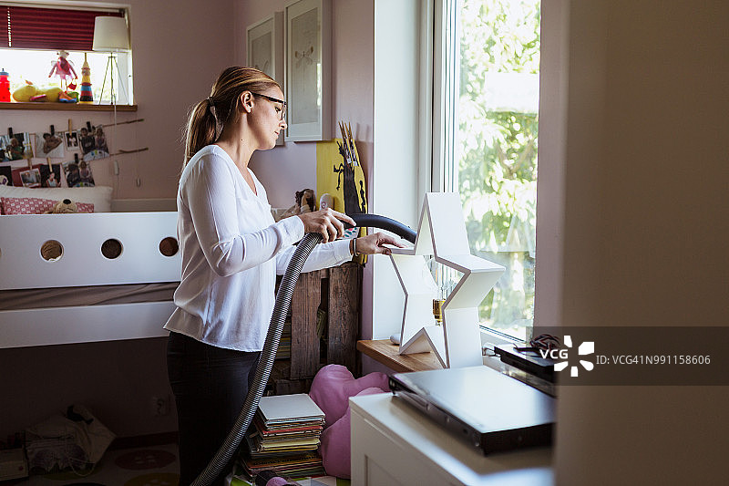 女人在家用真空吸尘器清洁卧室图片素材