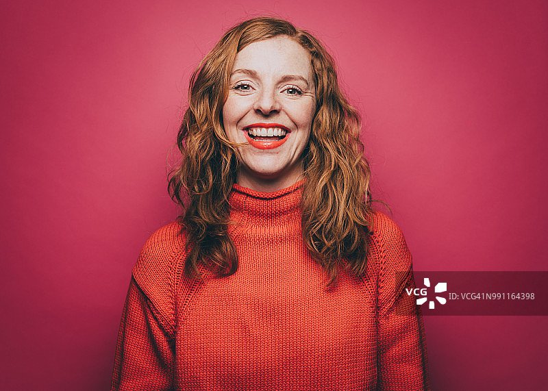 粉色背景下的橙色上衣微笑女性肖像图片素材