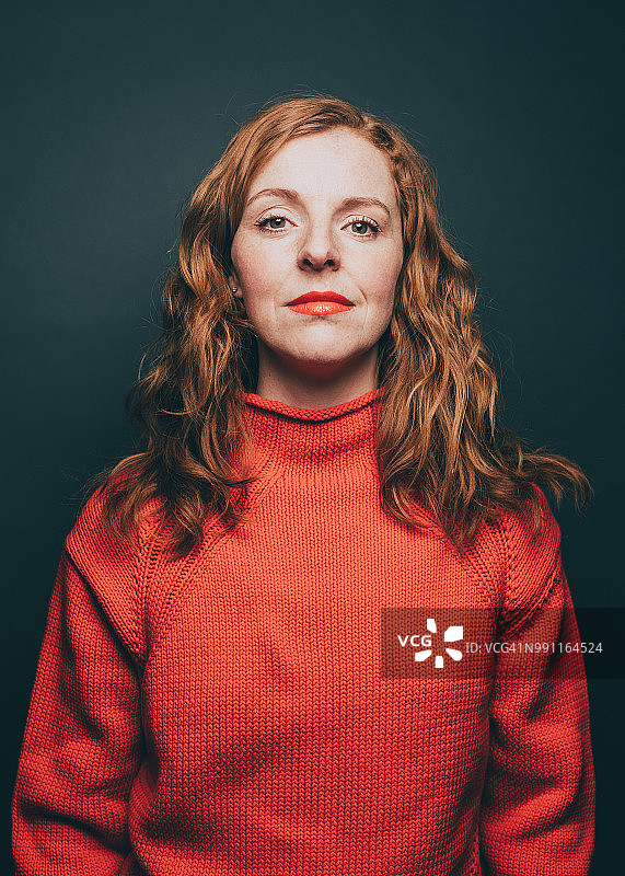 身穿橙色上衣自信女性的肖像，灰色背景图片素材
