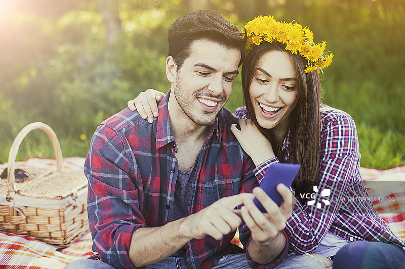 幸福的夫妇在野餐时用手机上网图片素材
