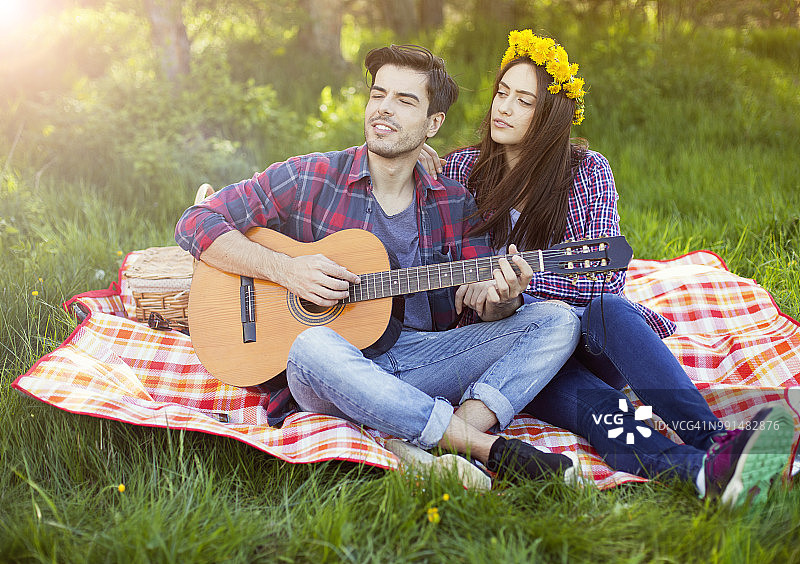 情侣在草地上野餐，弹吉他图片素材