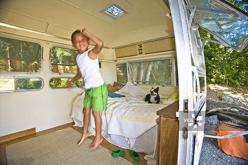 男孩和狗在露营车的床上图片素材