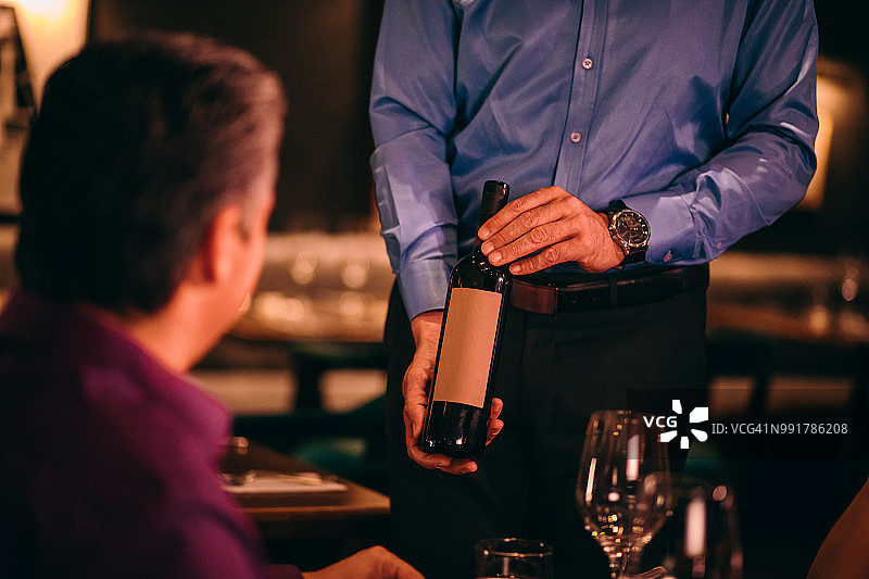 侍酒师在上菜前向高级餐厅顾客展示葡萄酒图片素材