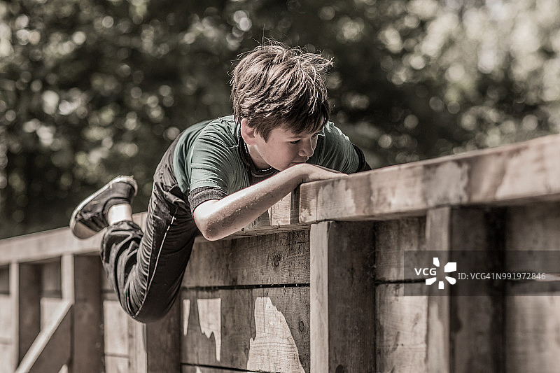 青少年男孩在泥浆障碍赛中运动图片素材