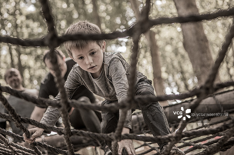 在公共泥地障碍赛的绳索桥上运动的青少年男孩图片素材