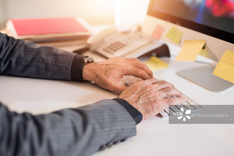 老年商人使用电脑键盘的特写图片素材