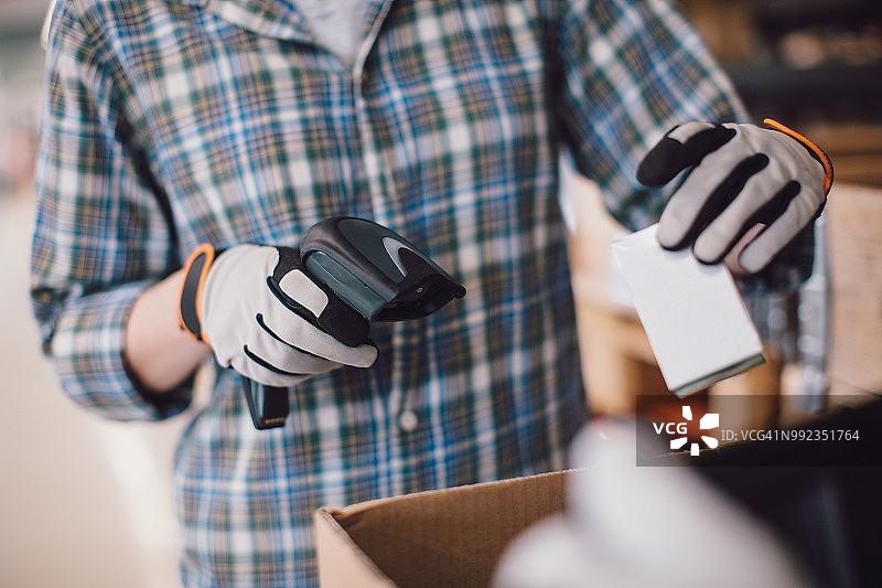 女同事在仓库用条形码扫描器扫描产品的腰部特写图片素材