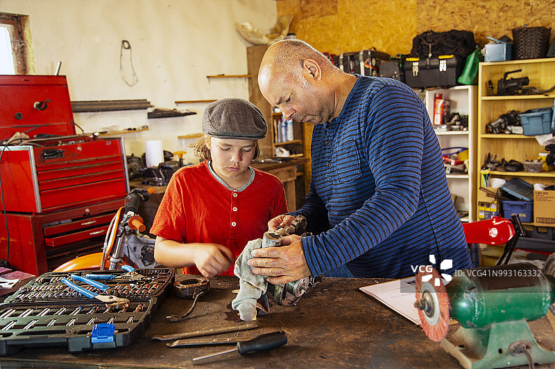 父亲和儿子在车间修理越野摩托车引擎图片素材
