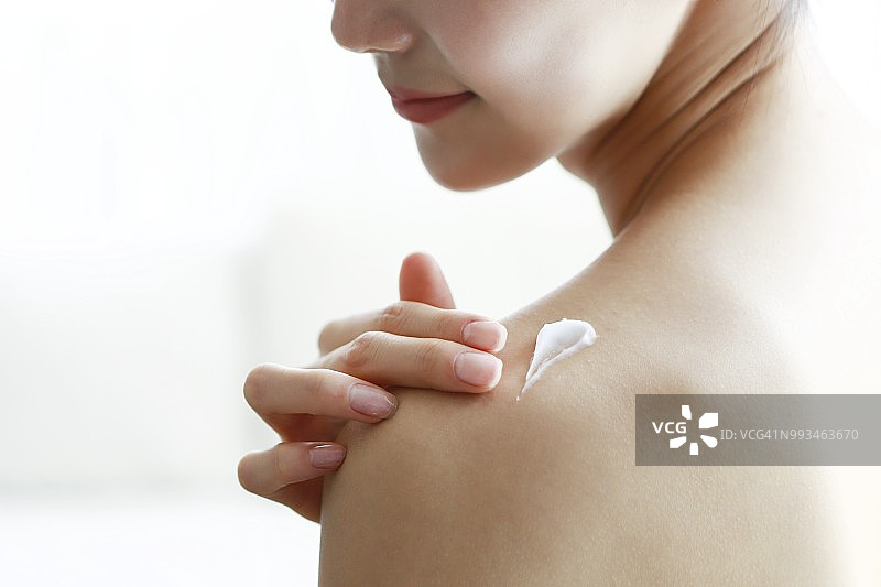 女性在肩上涂抹润肤露图片素材
