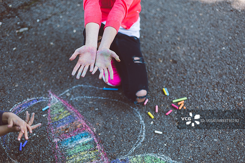 孩子们在沥青上用粉笔画画图片素材
