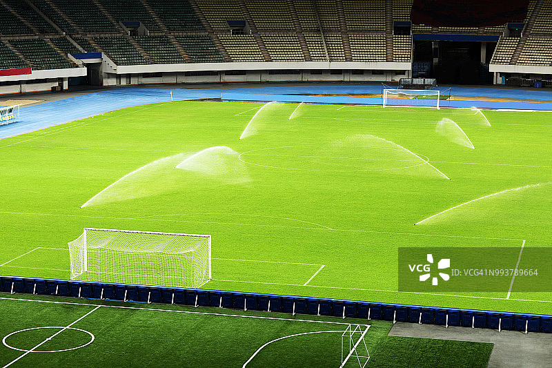 夜晚的空足球场和洒水系统图片素材