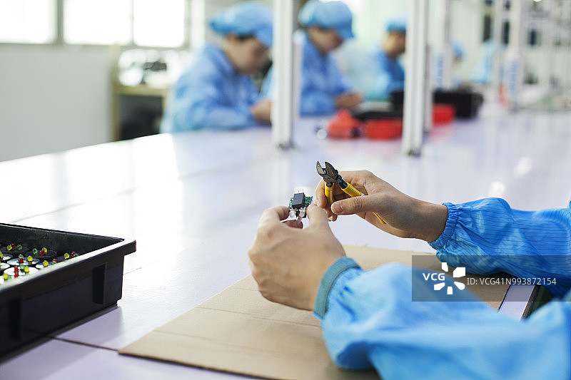 中国东莞LED打火机厂的工人拿着二极管图片素材