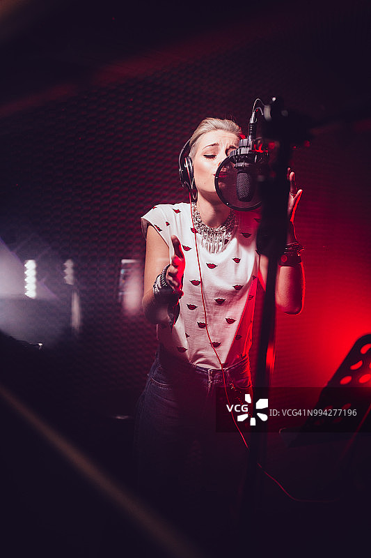 在专业音乐工作室唱歌和录音的时髦女人图片素材