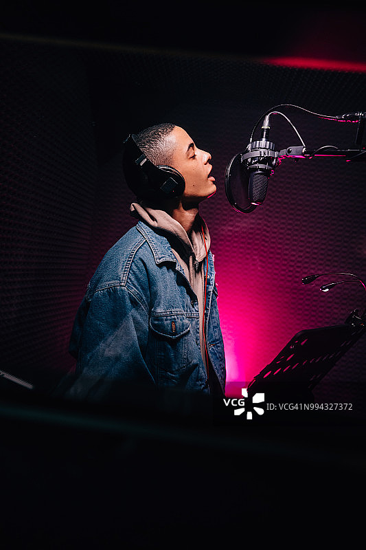 在音乐工作室唱歌和录音的年轻流行音乐家图片素材