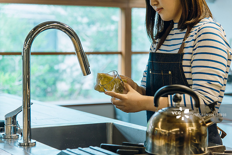在厨房擦玻璃的年轻女人图片素材