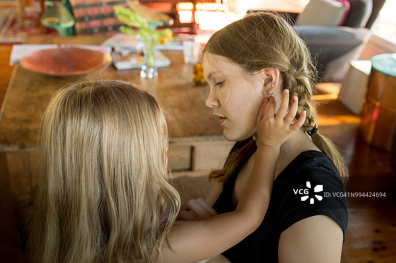 一个5岁女孩看着一个15岁女孩的耳洞图片素材