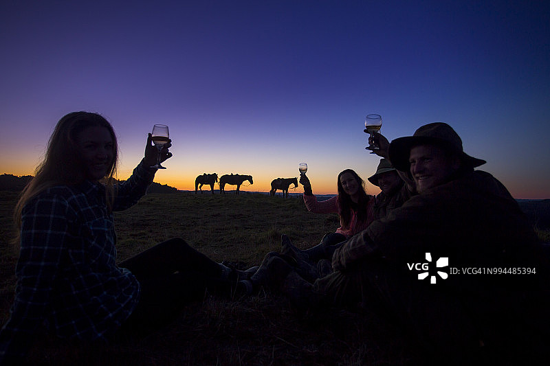 一群骑马者前往山顶，在旺加努伊国家公园欣赏日落并品尝葡萄酒图片素材
