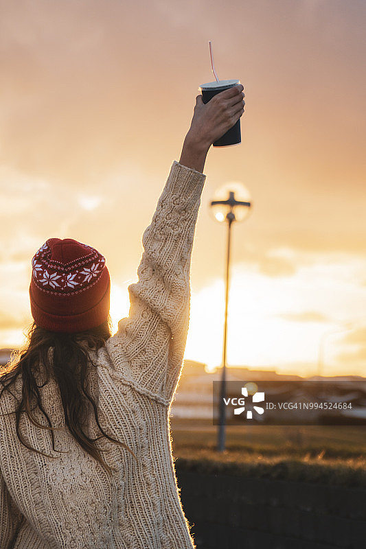 冰岛日落时分手持咖啡的年轻女子图片素材