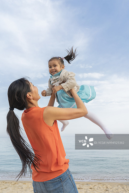 快乐的妈妈和女儿在沙滩上玩图片素材