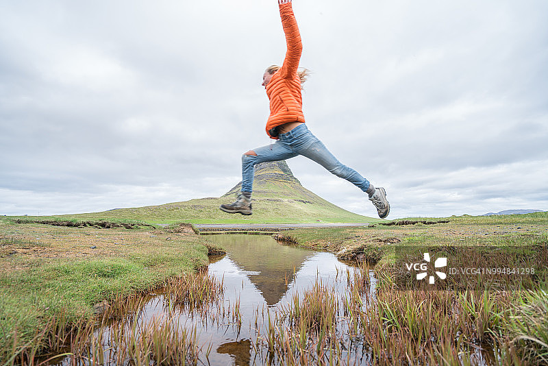 冰岛峡湾：年轻女子在教堂山跳跃图片素材