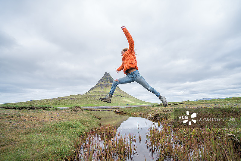 冰岛峡湾：年轻女子在教堂山跳跃图片素材
