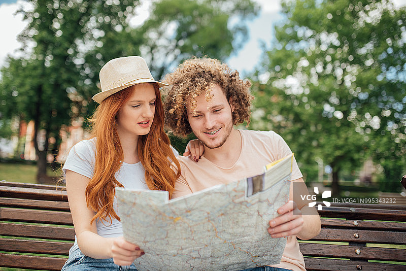 年轻游客情侣坐在长椅上看地图图片素材