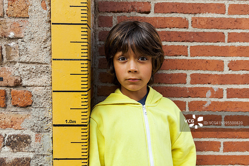 倚靠着量尺的怀疑男孩肖像图片素材