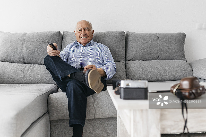 年长的男人在家里的沙发上看电视图片素材