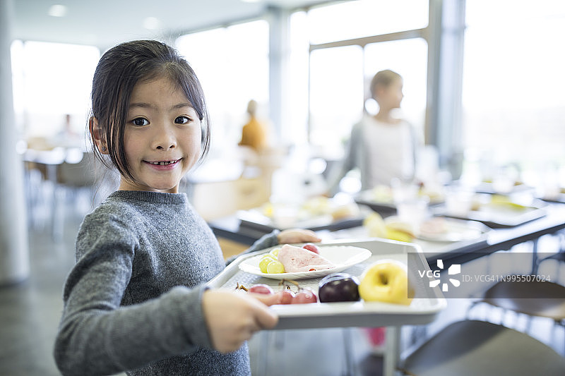 微笑的女学生肖像，在学校食堂里端托盘图片素材