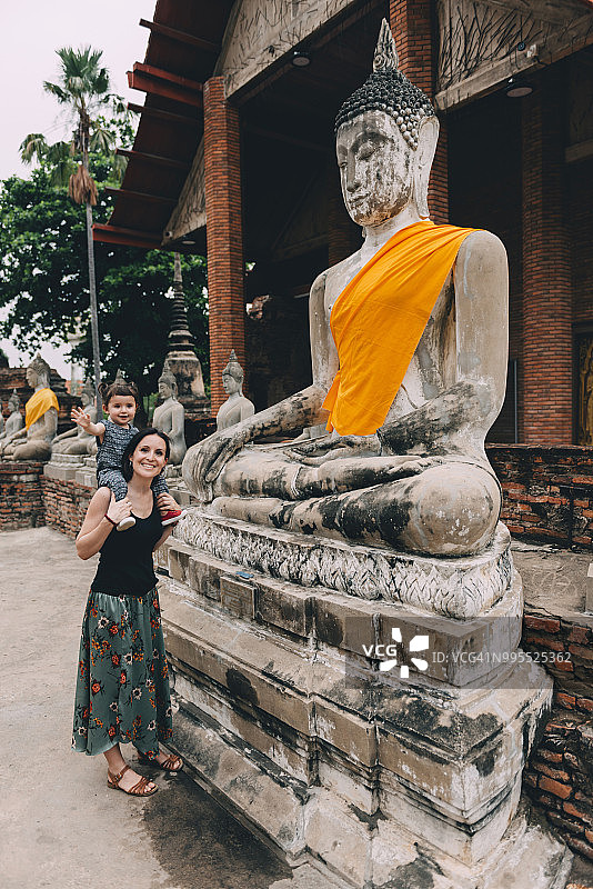 泰国阿瑜陀耶府，母亲和女儿站在崖差蒙空寺的佛像旁图片素材