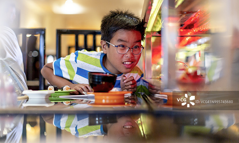 在旋转寿司餐厅里的10岁越南男孩图片素材