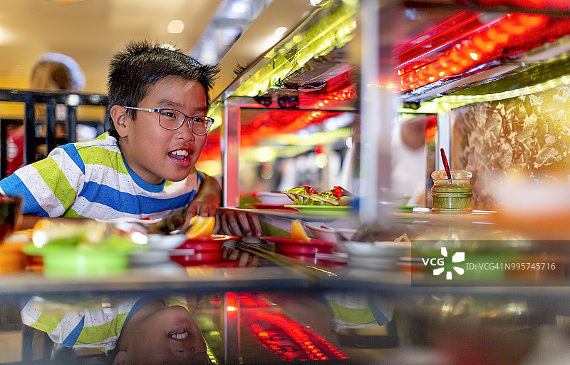 在旋转寿司餐厅里的10岁越南男孩图片素材