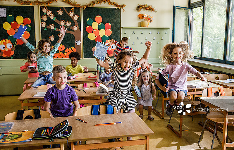 快乐的学生在教室的课桌间跳跃玩耍图片素材