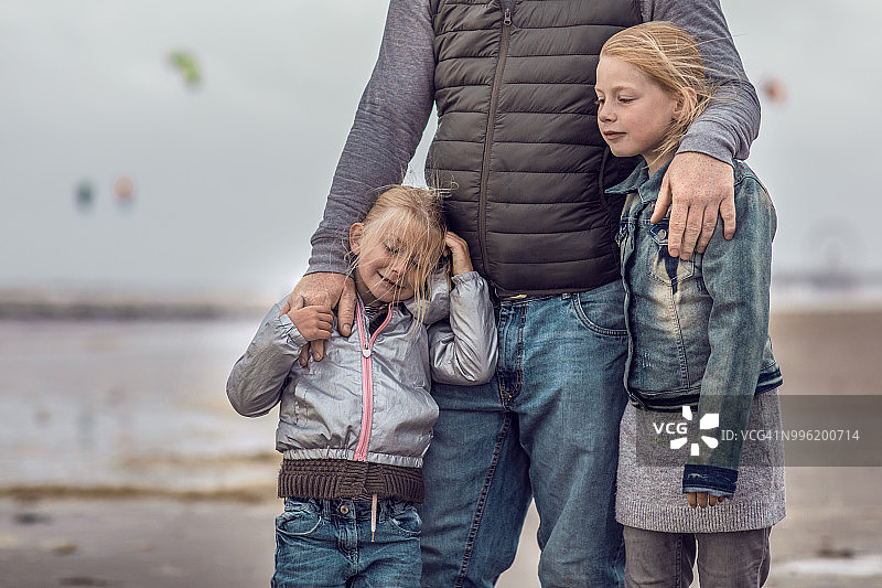 单亲父亲和女儿们在冬季海滩上玩家庭游戏图片素材