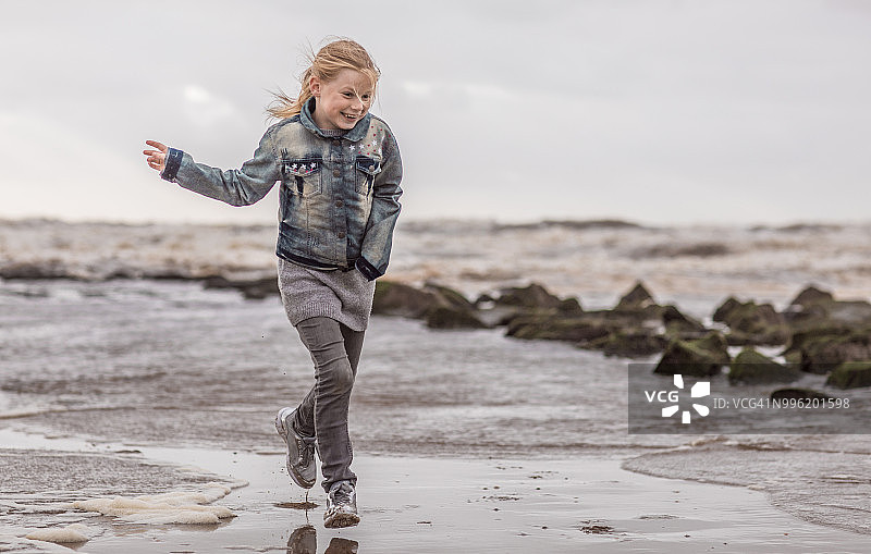 在冬季海滩上享受自由的年轻金发女孩图片素材